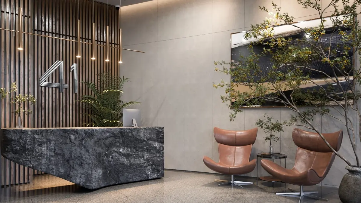 41 Business District – Lobby mit dunklem Steintresen, Holzlamellenwand und Lounge-Sesseln aus Leder
