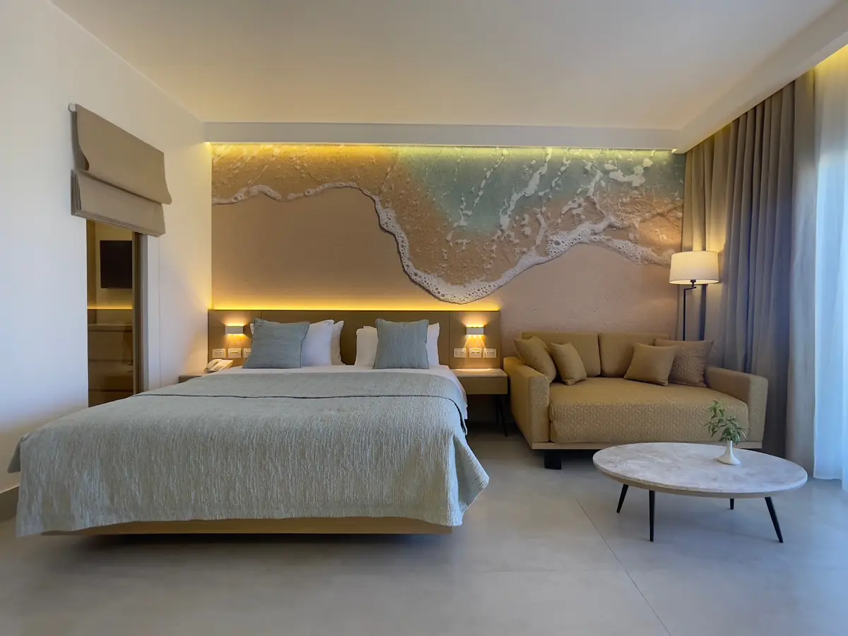 Amwaj Resort Rooms Extension – Guest room with breaking-wave relief above the bed, sofa and oval coffee table