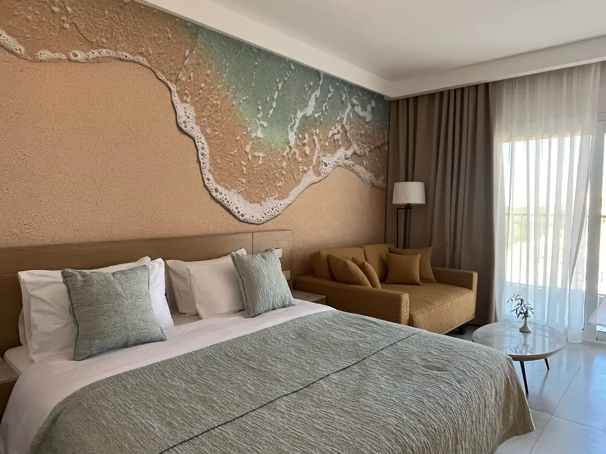 Amwaj Resort Rooms Extension – Bed beneath the sculpted wave relief, with balcony doors behind sheer curtains