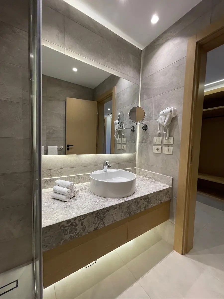 Amwaj Resort Rooms Extension – Grey stone bathroom with an under-lit granite vanity and vessel basin