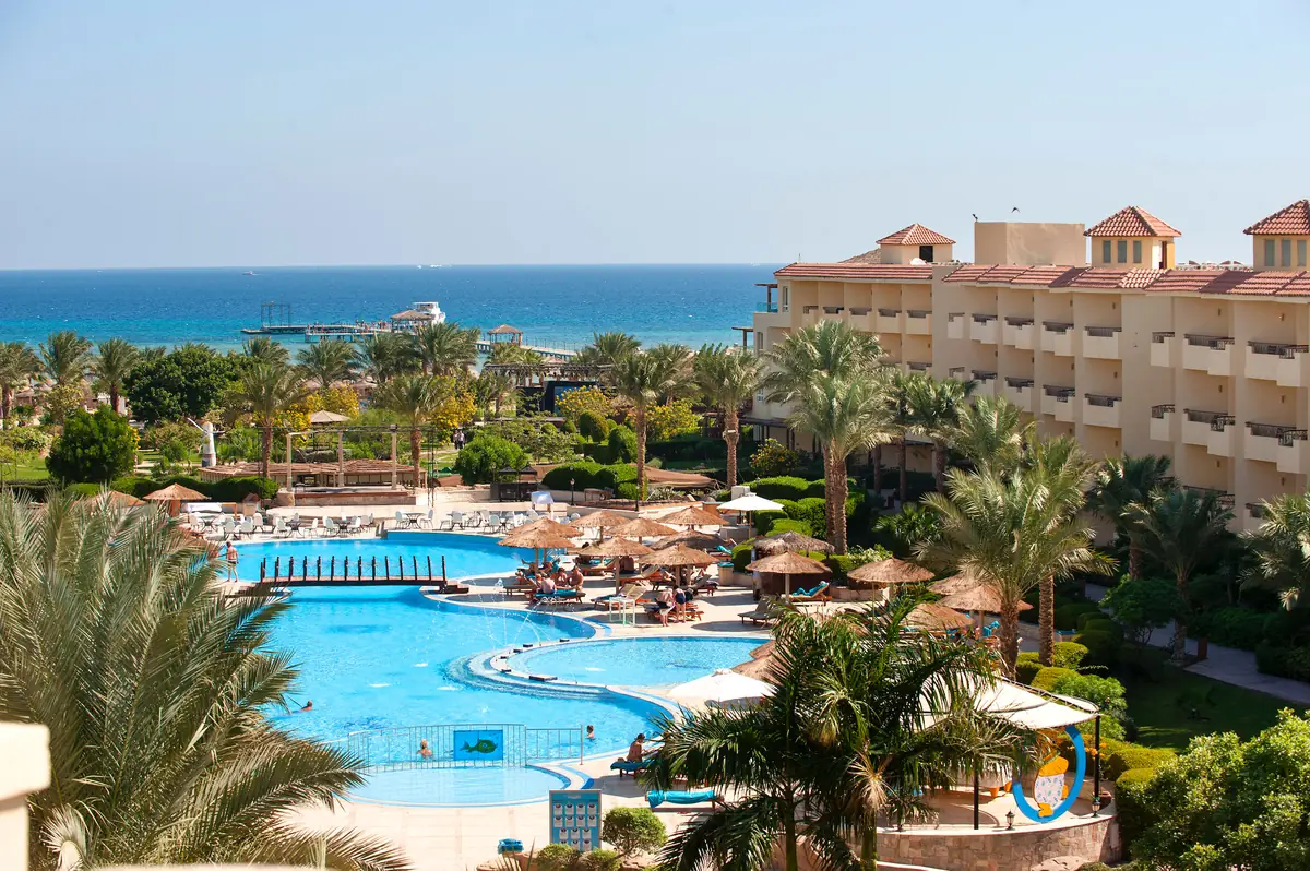 Amwaj Soma Hotel & Spa – مسابح وحدائق نخيل أسفل جناح متدرج بلون التيراكوتا والبحر في الخلفية