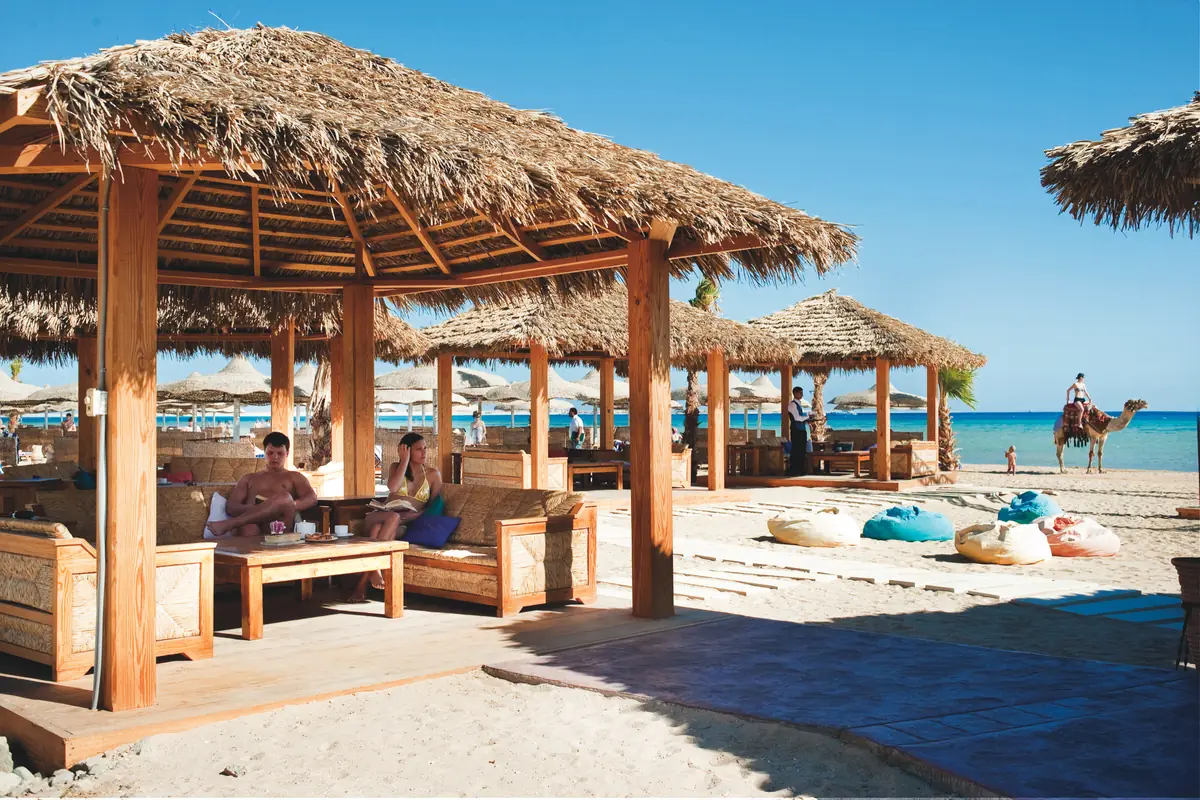 Amwaj Soma Hotel & Spa – مظلات شاطئية من القش بمقاعد خشبية وأكياس جلوس وجمل على الشاطئ