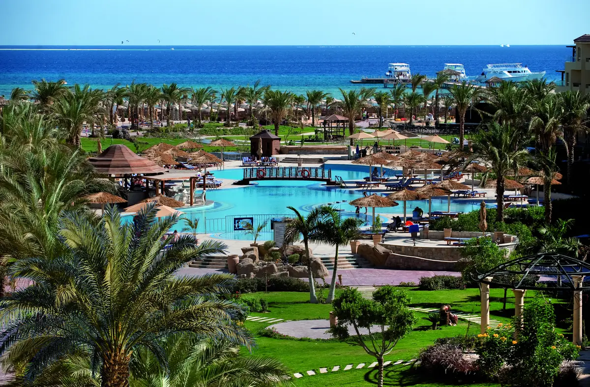 Amwaj Soma Hotel & Spa – حدائق نخيل ومسطحات خضراء تنحدر نحو المسابح مع قوارب راسية قبالة الشاطئ