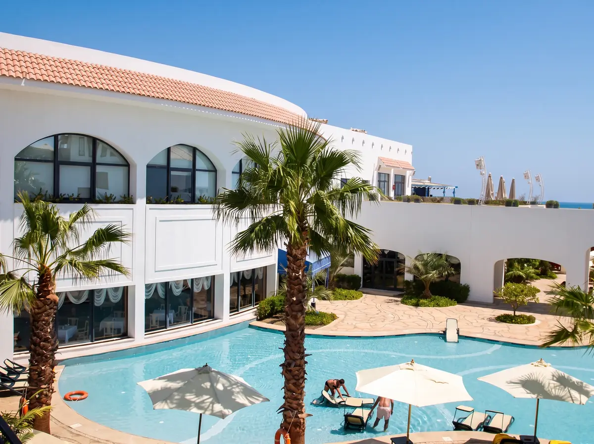 Blue Bay Resort Thalassotherapy Spa – Arched white façade and palms around a pool with parasols