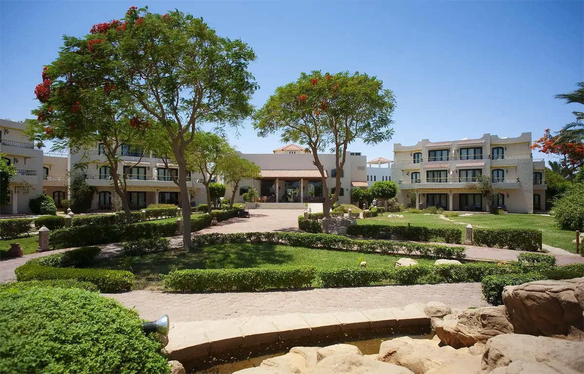 Lotus Bay Resort Renovation – Landscaped gardens with flowering trees and hedges before low guest buildings