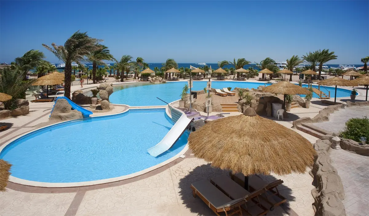 Lotus Bay Resort Renovation – Pool with blue and white water slides and a thatched parasol in front