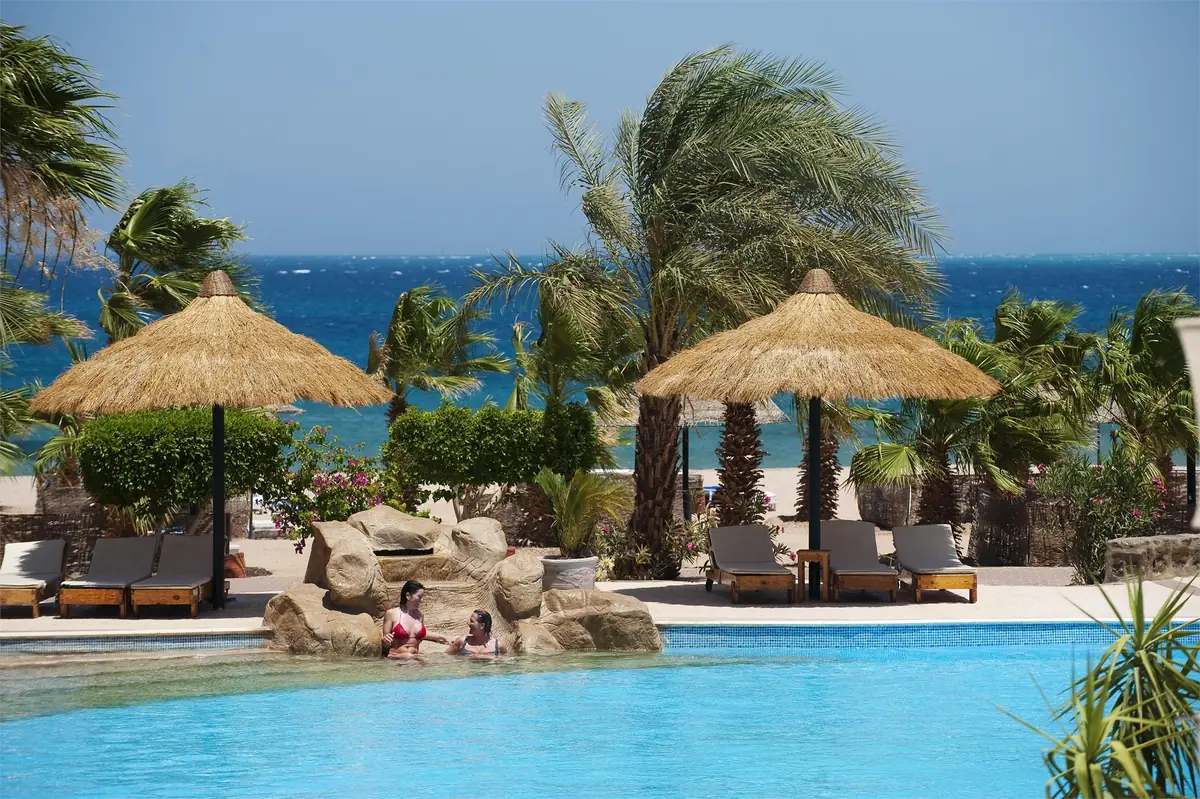 Lotus Bay Resort Renovation – Pool edge with rock outcrop, sun loungers and thatched parasols before the sea