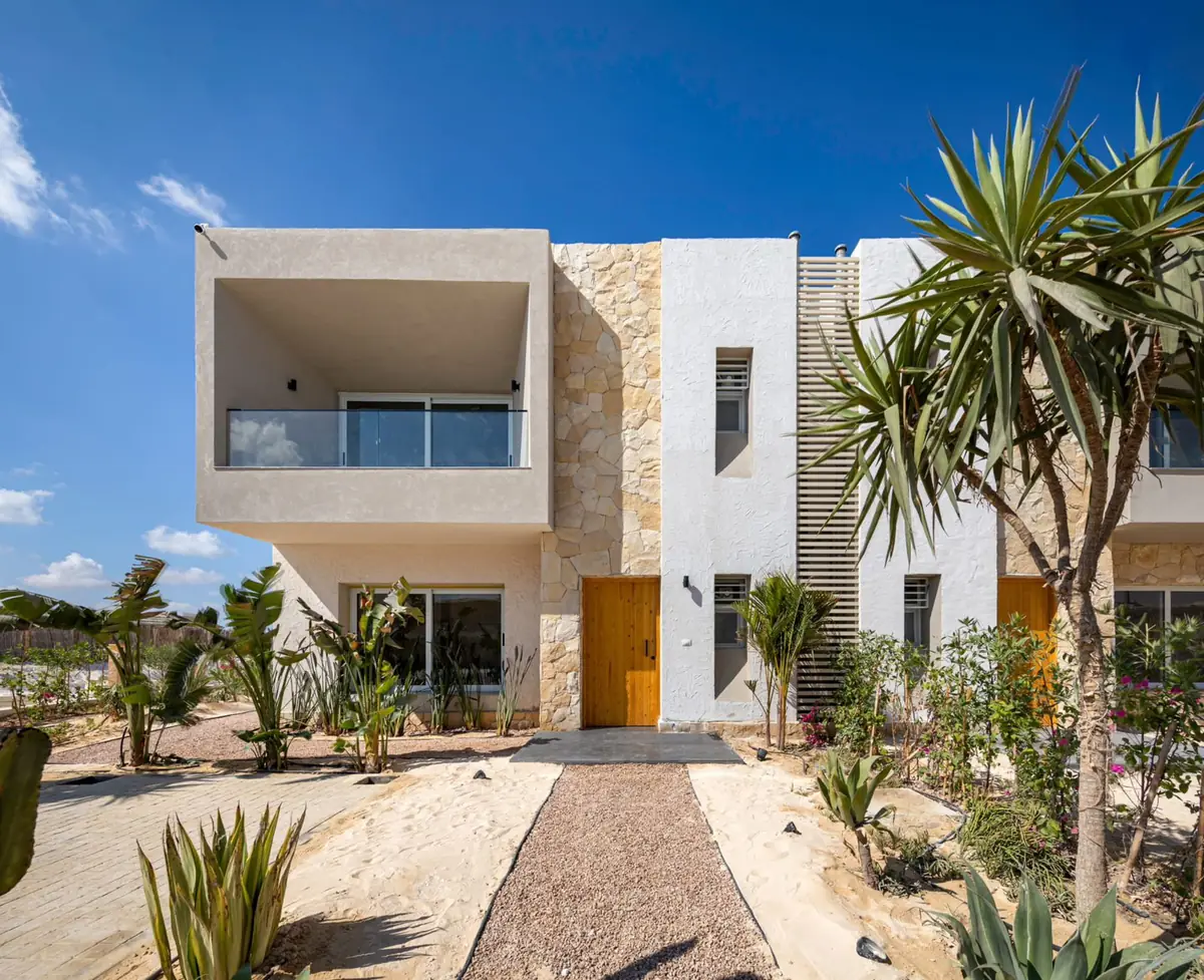 Masyaf Ras Al-Hekma – Townhouse pair with stone cladding, timber doors and a gravel desert-garden path