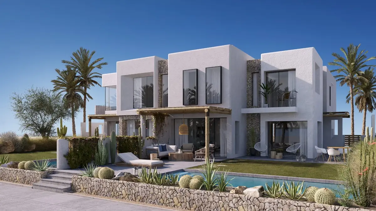 Masyaf Ras Al-Hekma – Row of white townhouses behind stone garden walls, cacti and a pool