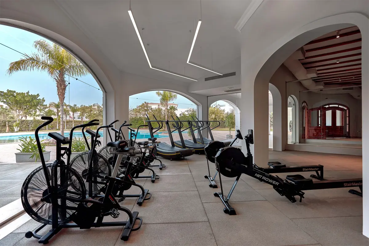 Move – Green Heights Sports Complex – Arcaded training terrace with air bikes, rowers and treadmills facing the pool