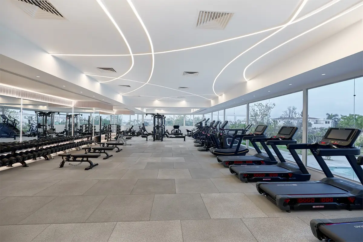 Move – Green Heights Sports Complex – Wide view of the glass-walled gym with weight benches and cardio rows