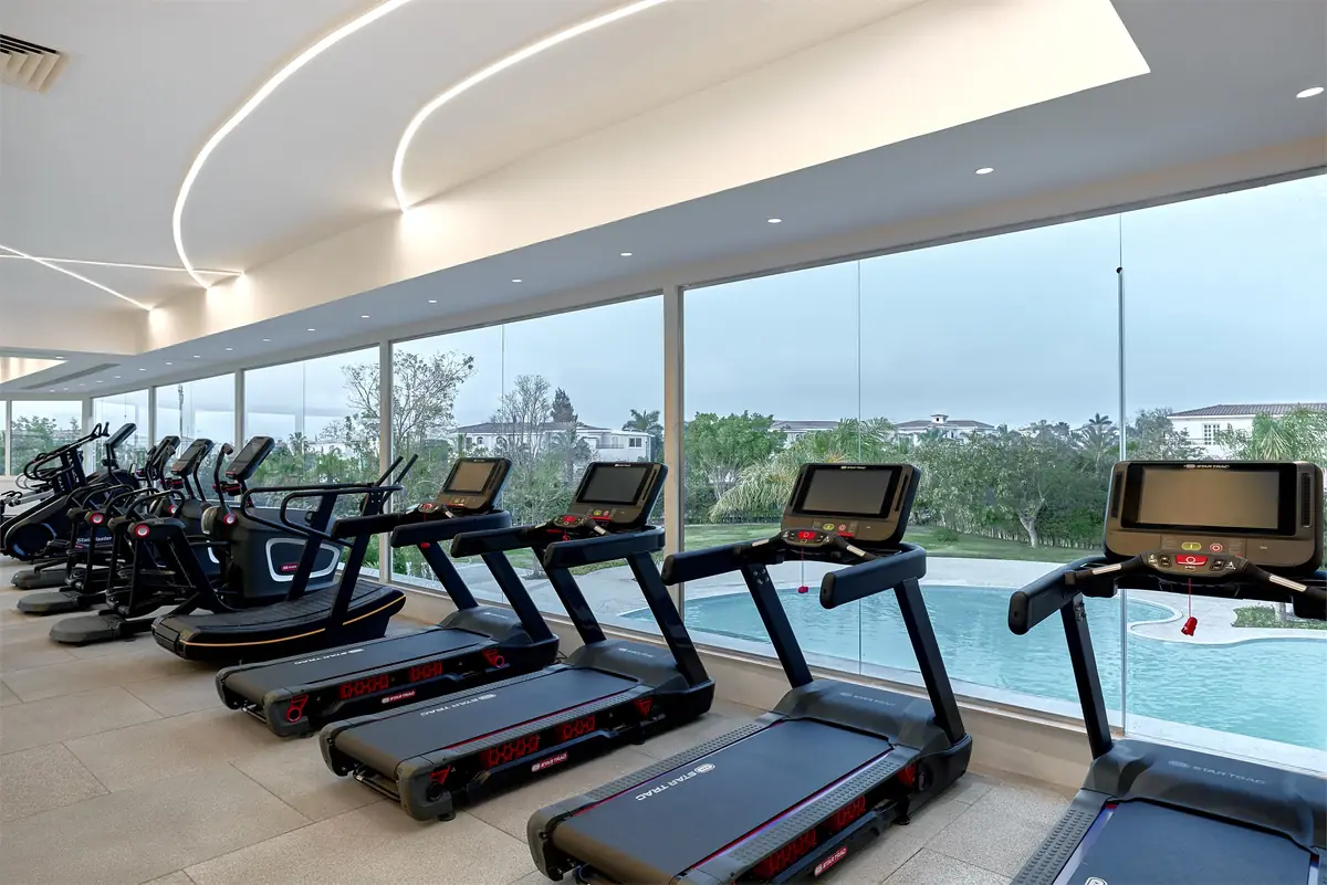 Move – Green Heights Sports Complex – Row of treadmills along a glass wall overlooking the pool and gardens