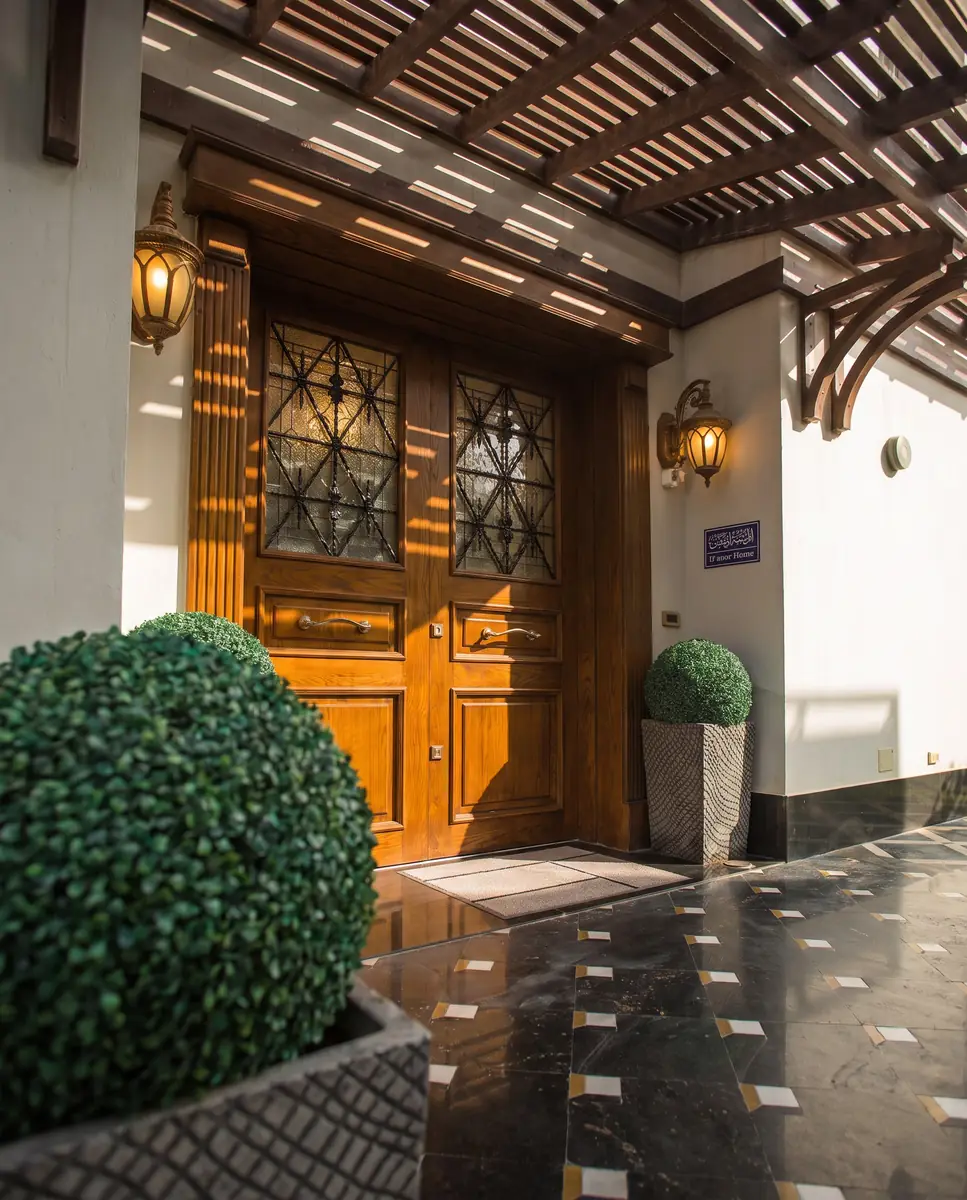 Mrs. M.A.'s Villa – Angled view of the carved timber entrance door beside a clipped topiary ball