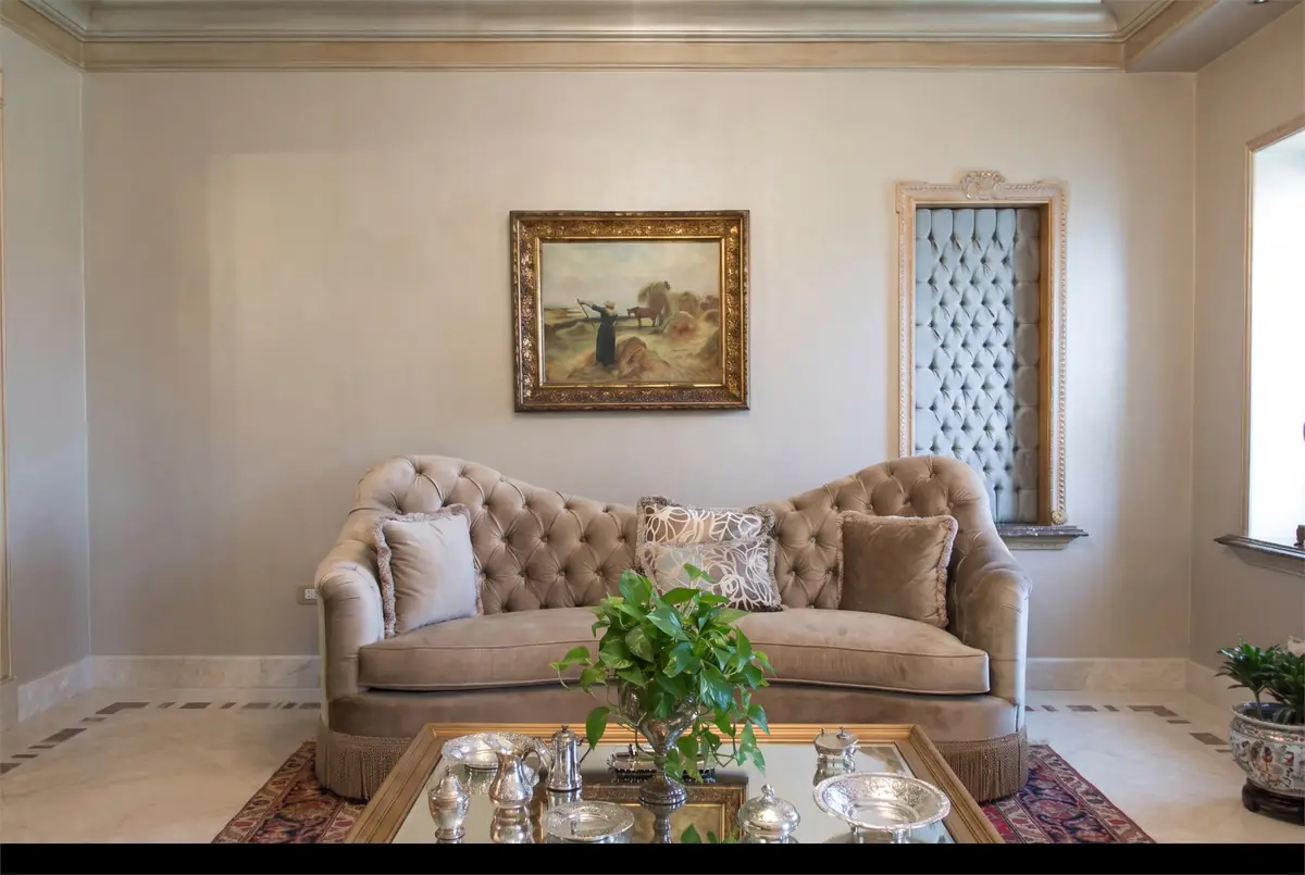 Mrs. M.A.'s Villa – Tufted velvet sofa beneath a framed landscape painting, with silverware on the table