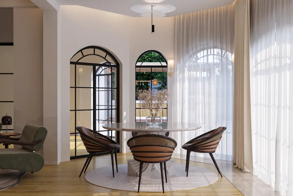 Mrs. S.T.'s Villa – V.24 – Round dining table with curved chairs before arched steel windows and sheer curtains