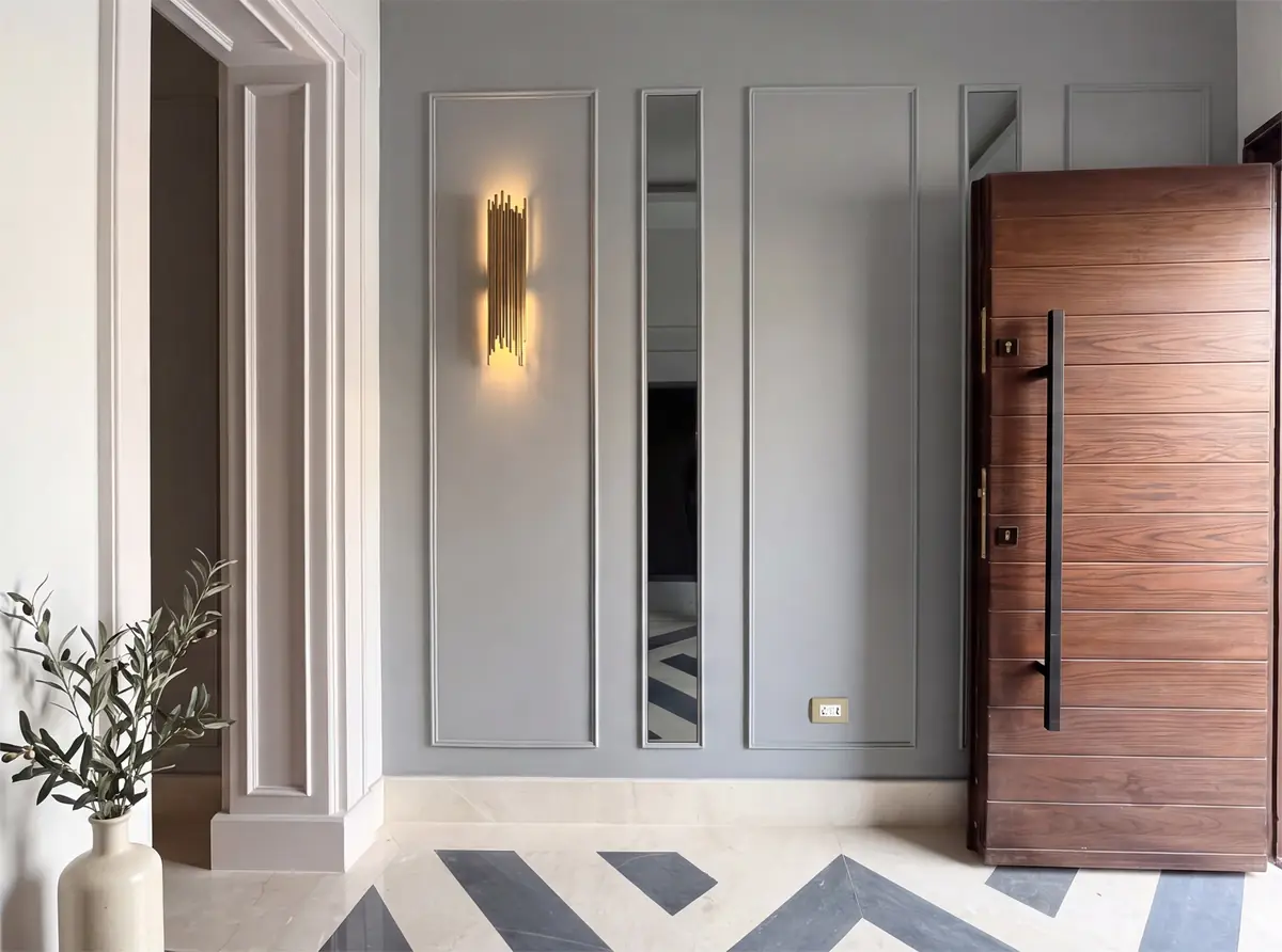 Prof. Dr. M.H. & Prof. Dr. Y.K.'s Villa – Entrance hall with grey panelled walls, walnut pivot door and chevron marble floor