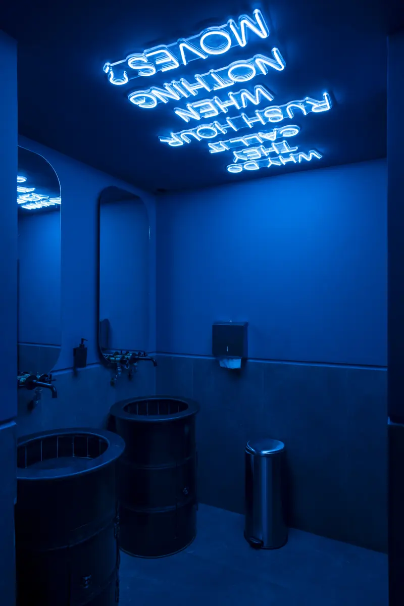 Rush – Sports Bar – Blau beleuchteter Waschraum mit Neon-Spruch über Kopf und Stahlfass-Waschbecken