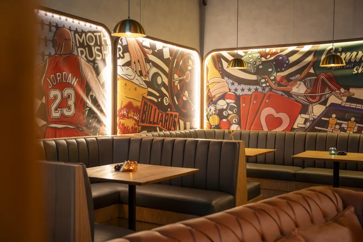 Rush – Sports Bar – Leder-Sitznischen unter hinterleuchteten Pop-Art-Wandbildern mit Basketball, Billard und Spielkarten