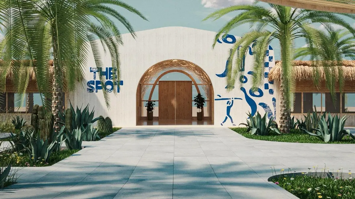 The Spot – Kite Center – Holztor im Rundbogen einer weißen Wand mit blau gemalten Surfmotiven